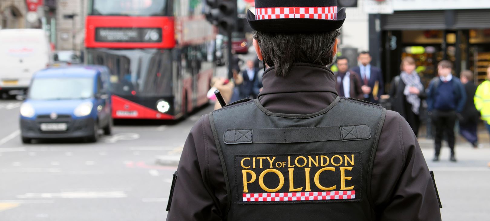 Image of the back of a female City of London police officer standing on the street with a red bus approaching used on Guildhawk government AI-powered translation solutions