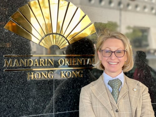 Photograph of Guildhawk Evernoon CEO Jurga Zilinskiene smiling outside the Mandarin Oriental Hotel Hong Kong with the hotel sign behind her 