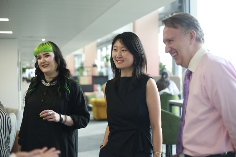 Image of members of Guildhawk team standing in the office smiling and discussing  